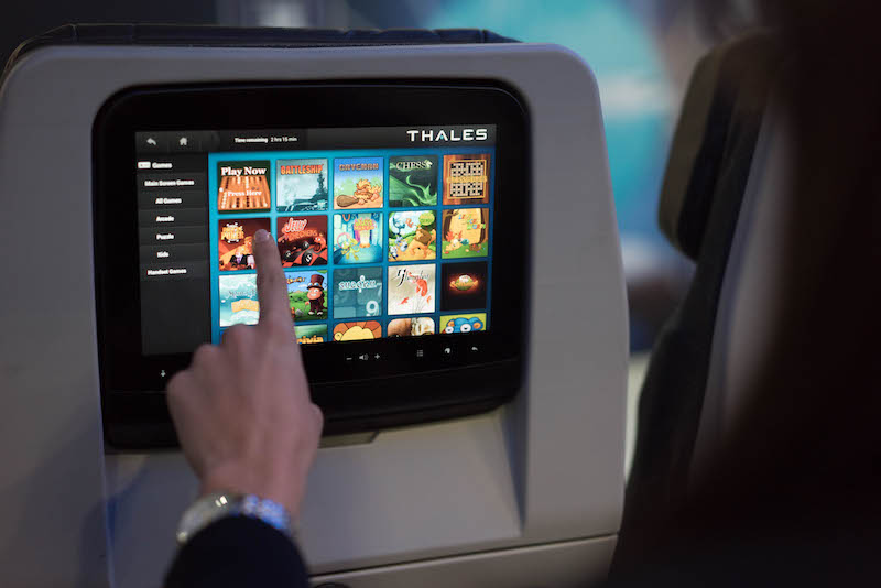 Close-up of an in-flight entertainment system screen on the back of an airline seat, displaying digital options for passengers during a flight.